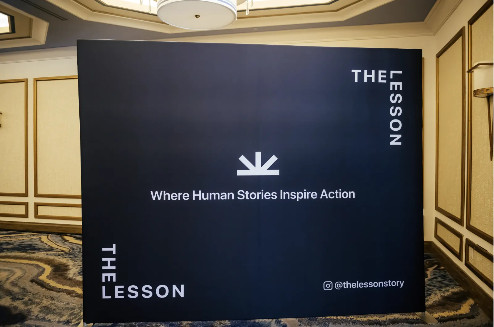 The Lesson branded backdrop reading Where Human Stories Inspire Action